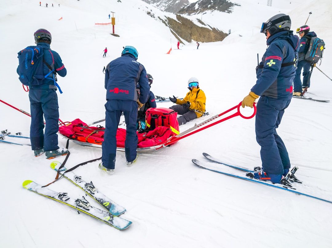 Skifahrer und Rettungsteam mit Ausrüstung auf einer Skipiste