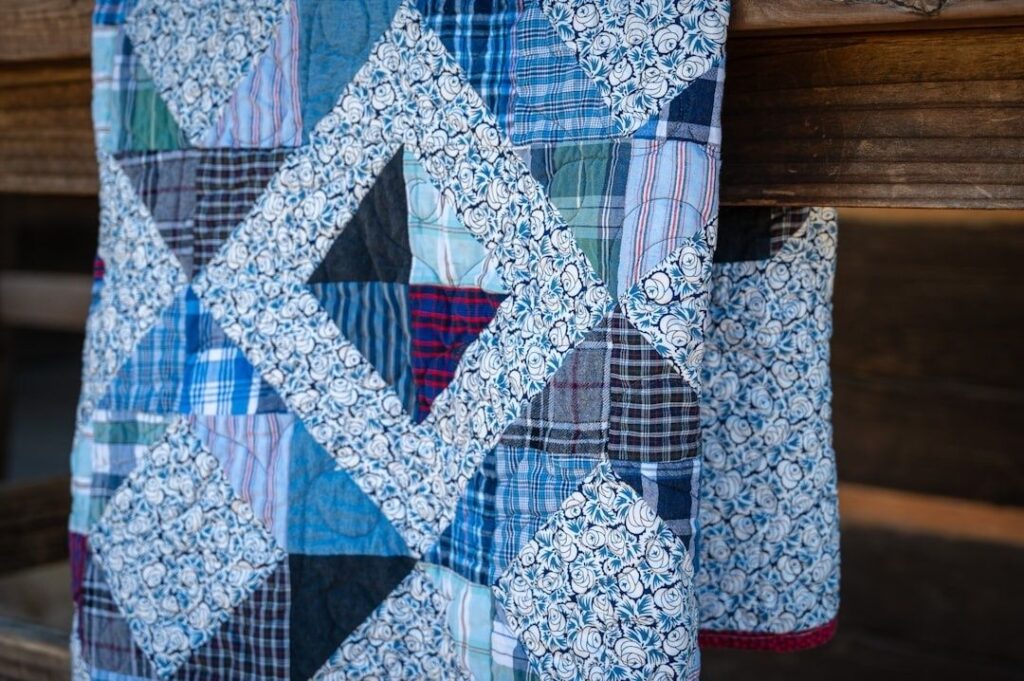 Blau-weißes Patchwork-Textil mit maritimen Mustern vor einer Holzwand